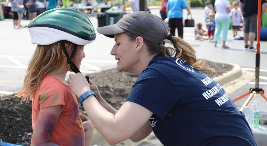 Staff member fitting child for bike helmet